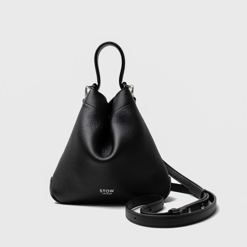 STOW London's Mini Curve in Black pebbled leather and detachable leather crossbody strap on a light grey background 