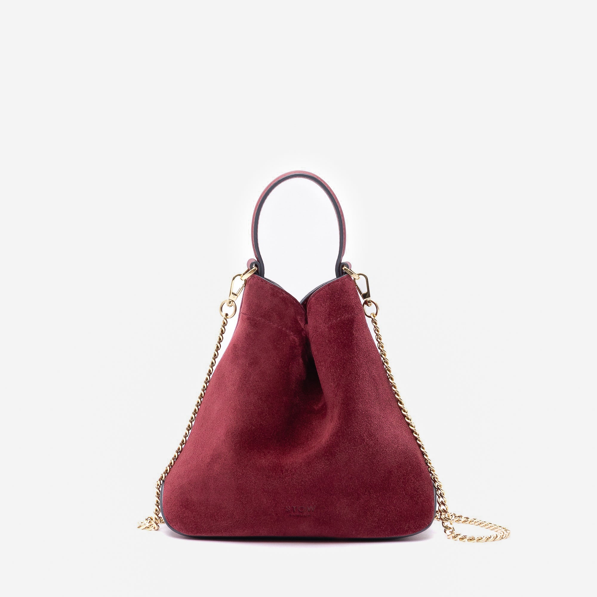 Stow London's Mini Curve in Burgundy suede leather and detachable gold chain crossbody strap on a light grey background 