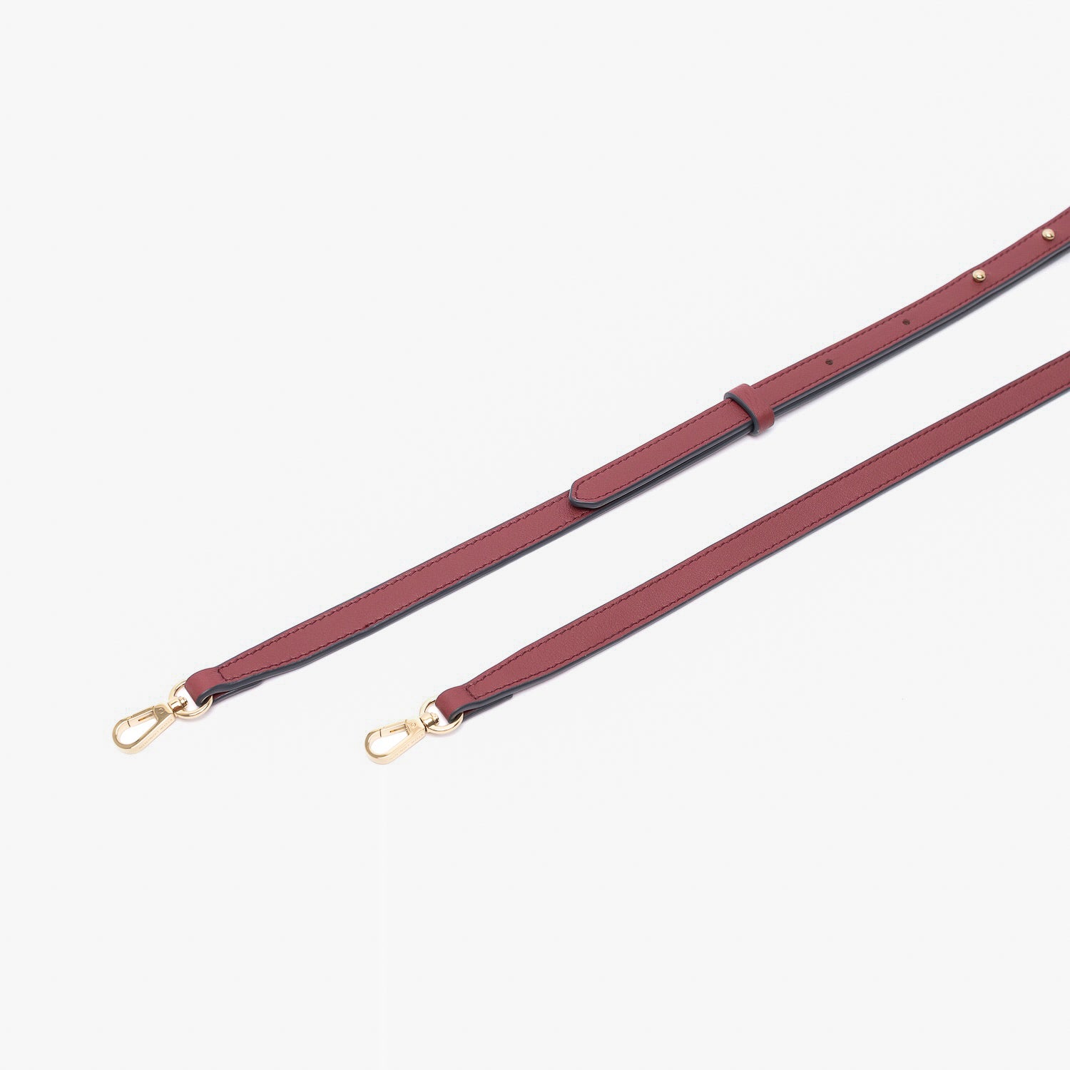 Close up of the detachable leather crossbody strap for STOW London's Mini Curve in Burgundy suede leather on a light grey background 