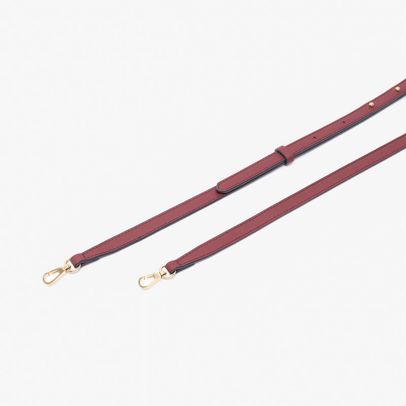 Close up of the detachable leather crossbody strap for STOW London's Mini Curve in Burgundy suede leather on a light grey background 