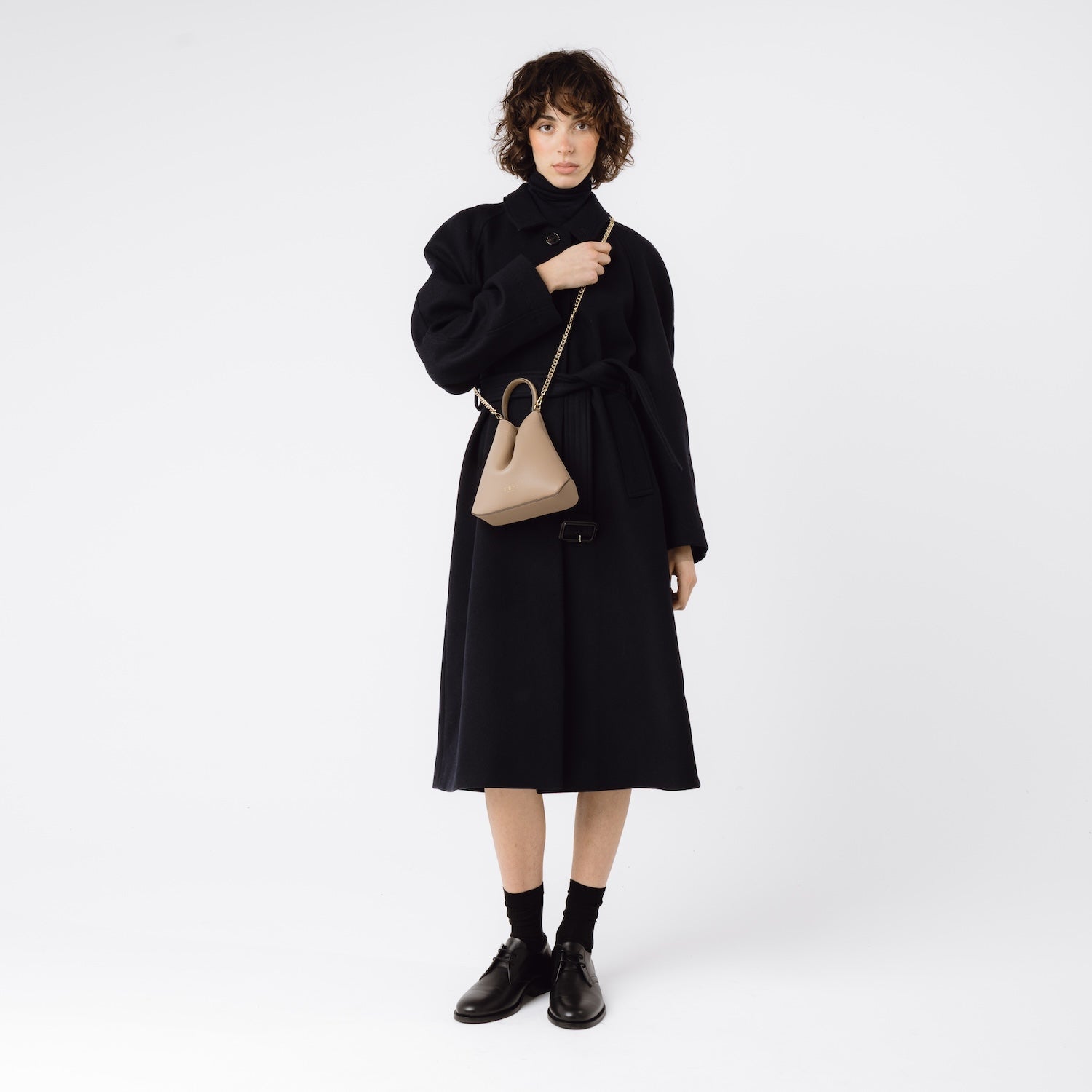 STOW London's Mini Curve in Camel leather worn crossbody on model with gold-plated chain on a white background