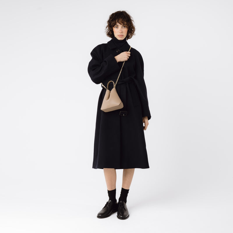 Model wearing STOW London's Mini Curve in Camel leather crossbody with gold-plated chain on a white background