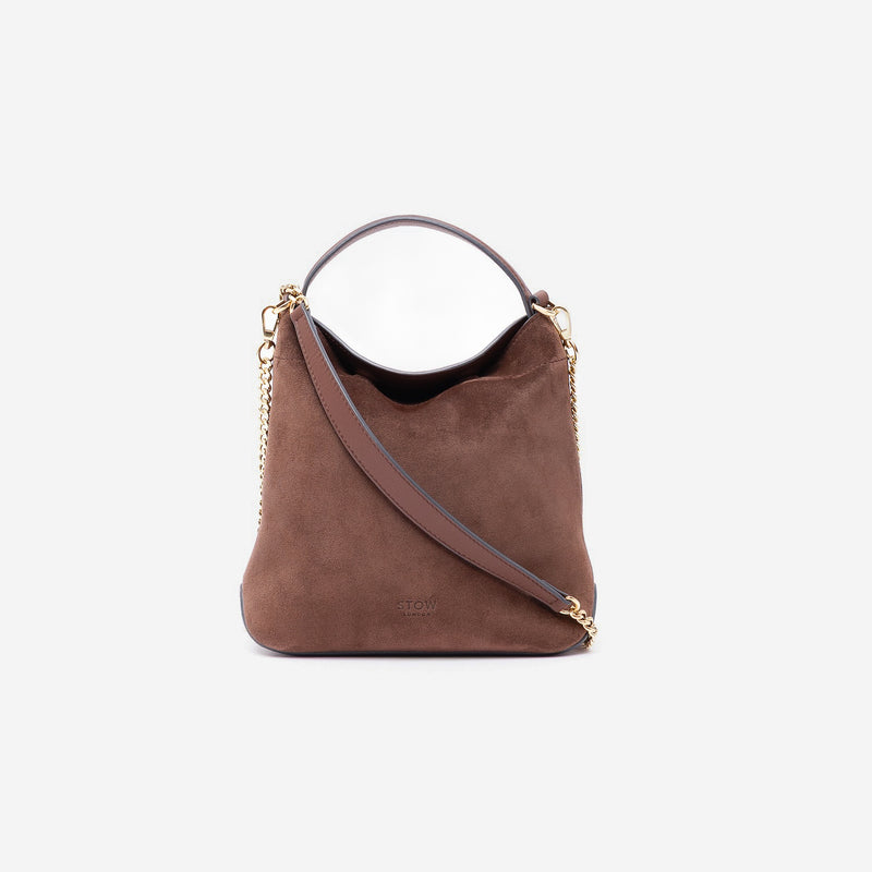 Stow London's Mini Curve in Chocolate suede leather and detachable gold chain crossbody strap styled as a flap bag on a light grey background 