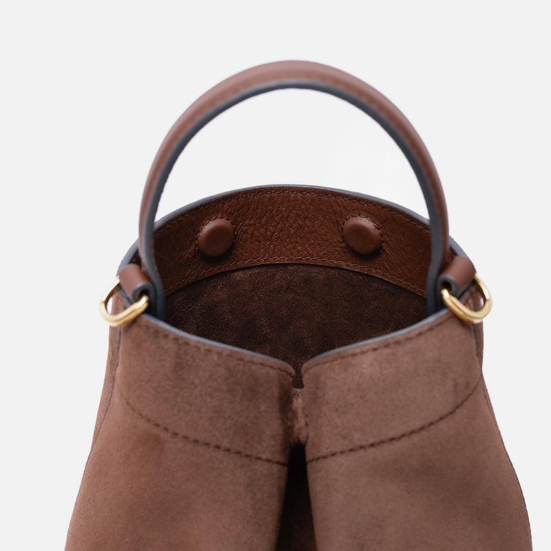 Close up of the top of Stow London's Mini Curve in Chocolate suede leather featuring hidden magnets, suede interior lining and gold hardware on a light grey background 