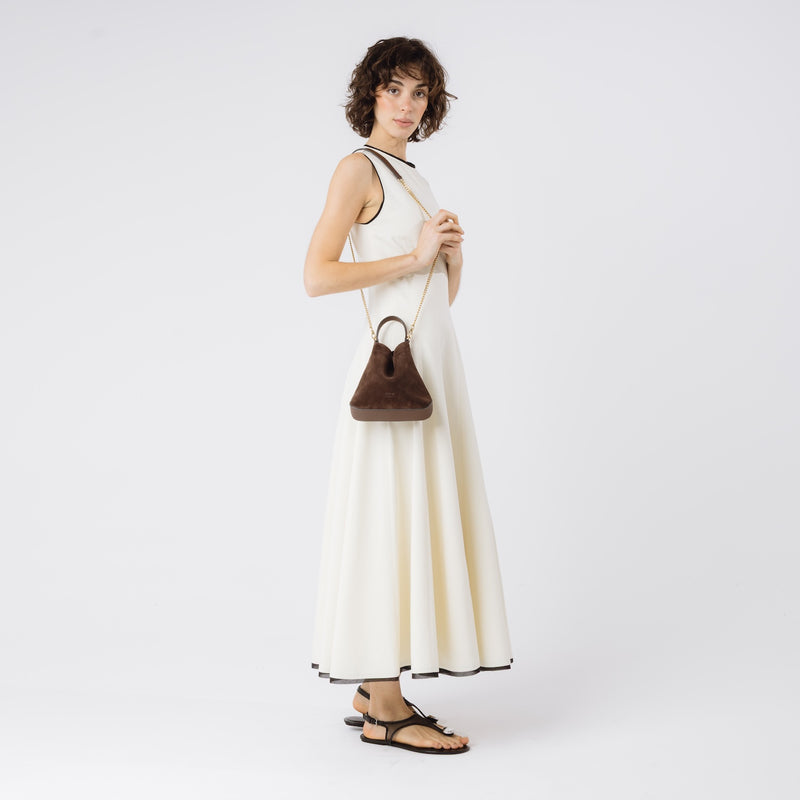 Model wearing Stow London's Mini Curve in Chocolate suede leather on her shoulder by detachable gold chain crossbody strap on a white background 