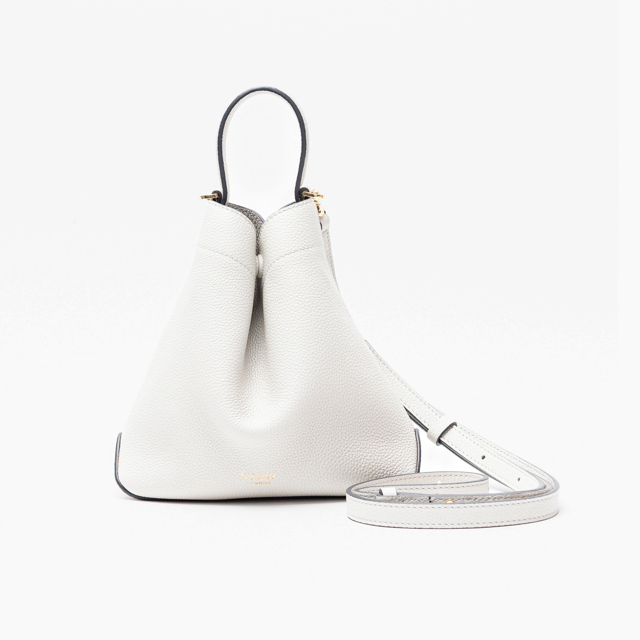 STOW London's Mini Curve in Cloud Grey pebbled leather and detachable leather crossbody strap on a light grey background 