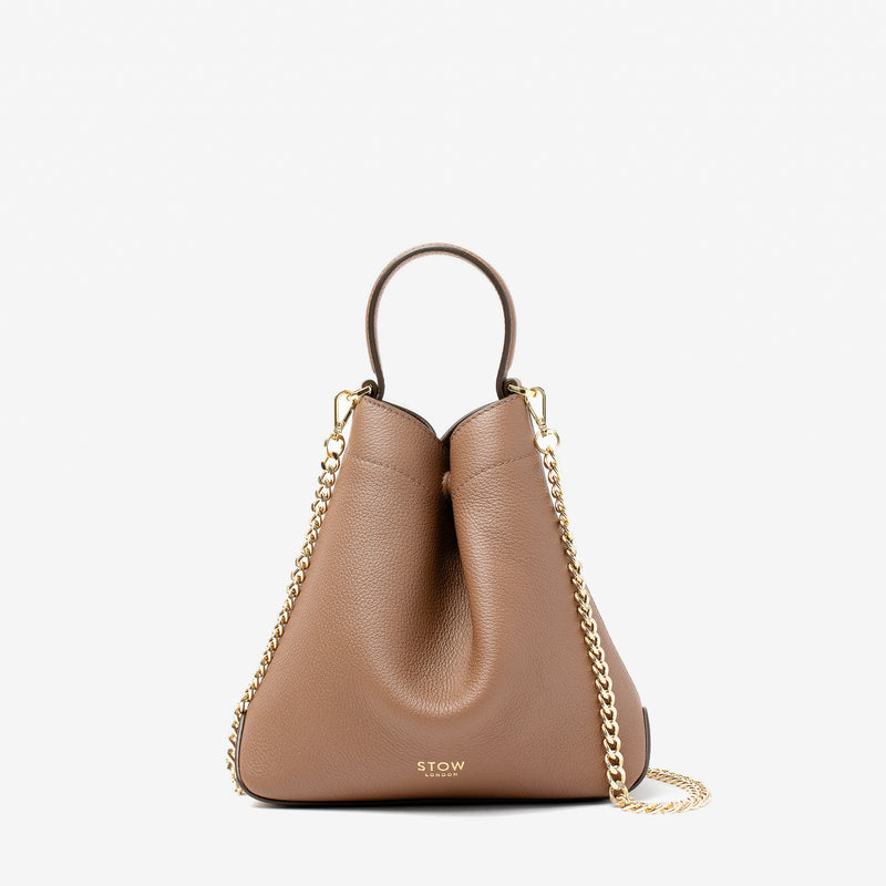 Stow London's Mini Curve in Mocha pebbled leather and detachable gold chain crossbody strap on a light grey background 