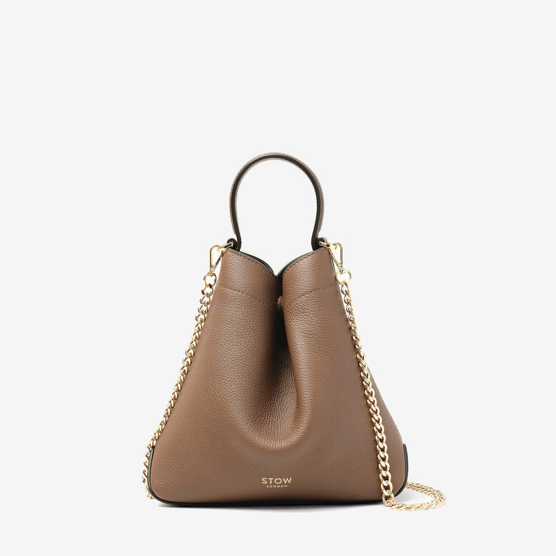 STOW London's Mini Curve in Mocha pebbled leather and detachable gold chain crossbody strap on a light grey background 