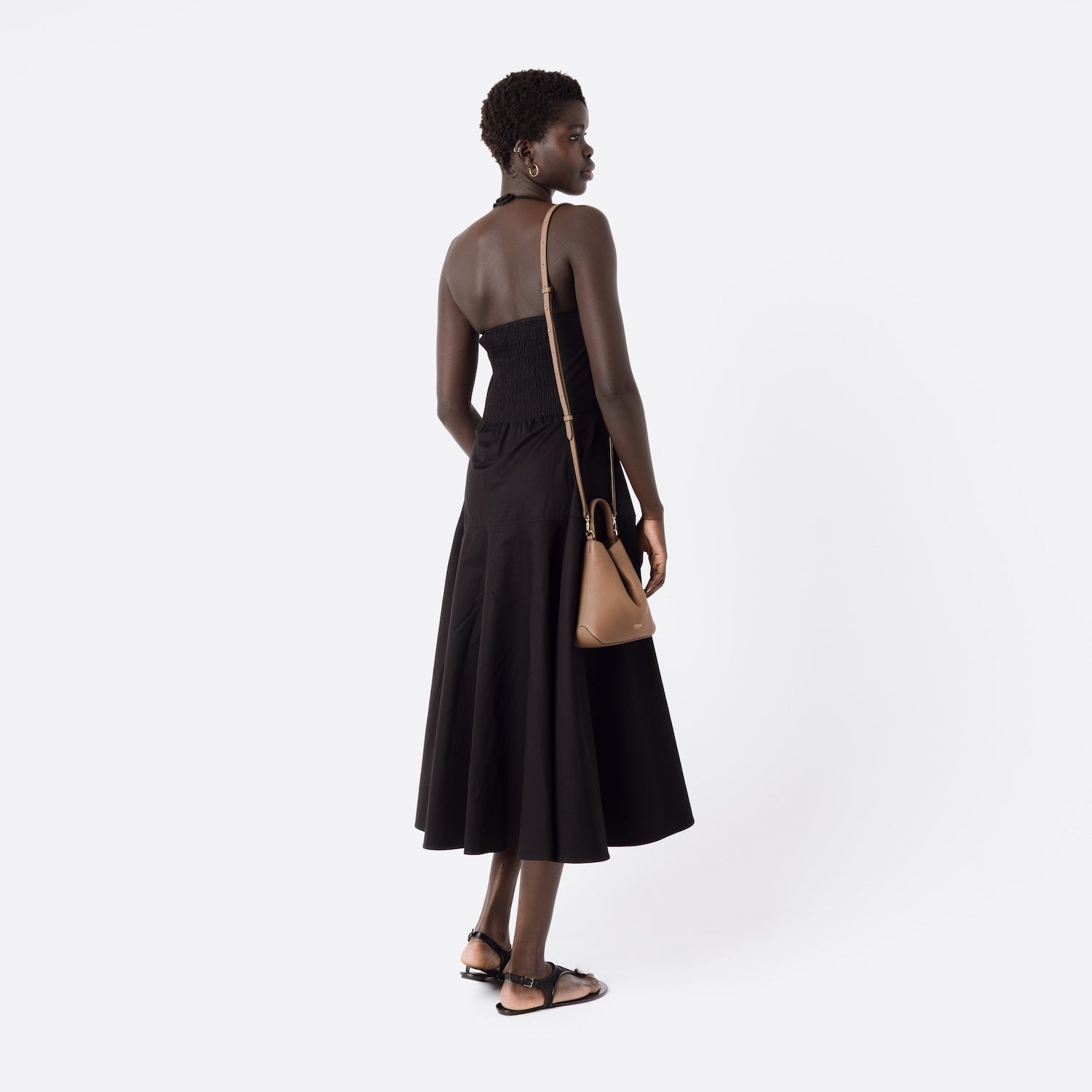 STOW London's Mini Curve in Mocha leather with detachable leather crossbody strap worn over model's shoulder on a white background