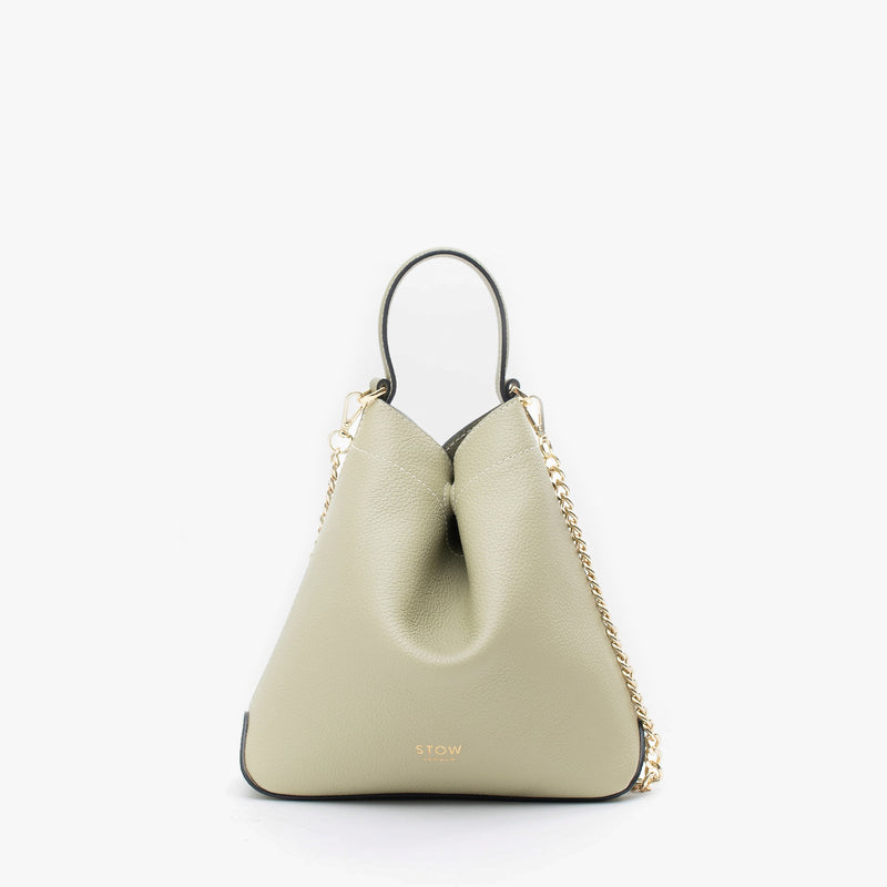 STOW London's Mini Curve in Pale Green pebbled leather and detachable gold chain crossbody strap on a light grey background 