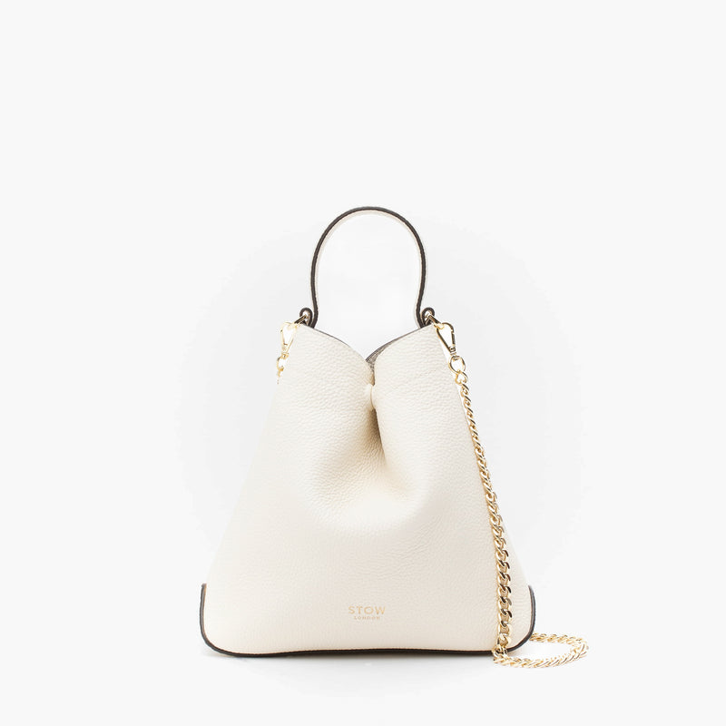 STOW London's Mini Curve in Spring Moon pebbled leather and detachable gold chain crossbody strap on a light grey background 