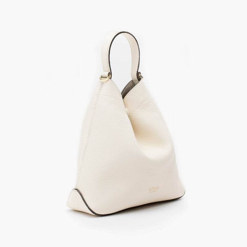 Off-axis view of STOW London's Mini Curve in Spring Moon pebbled leather on a light grey background 