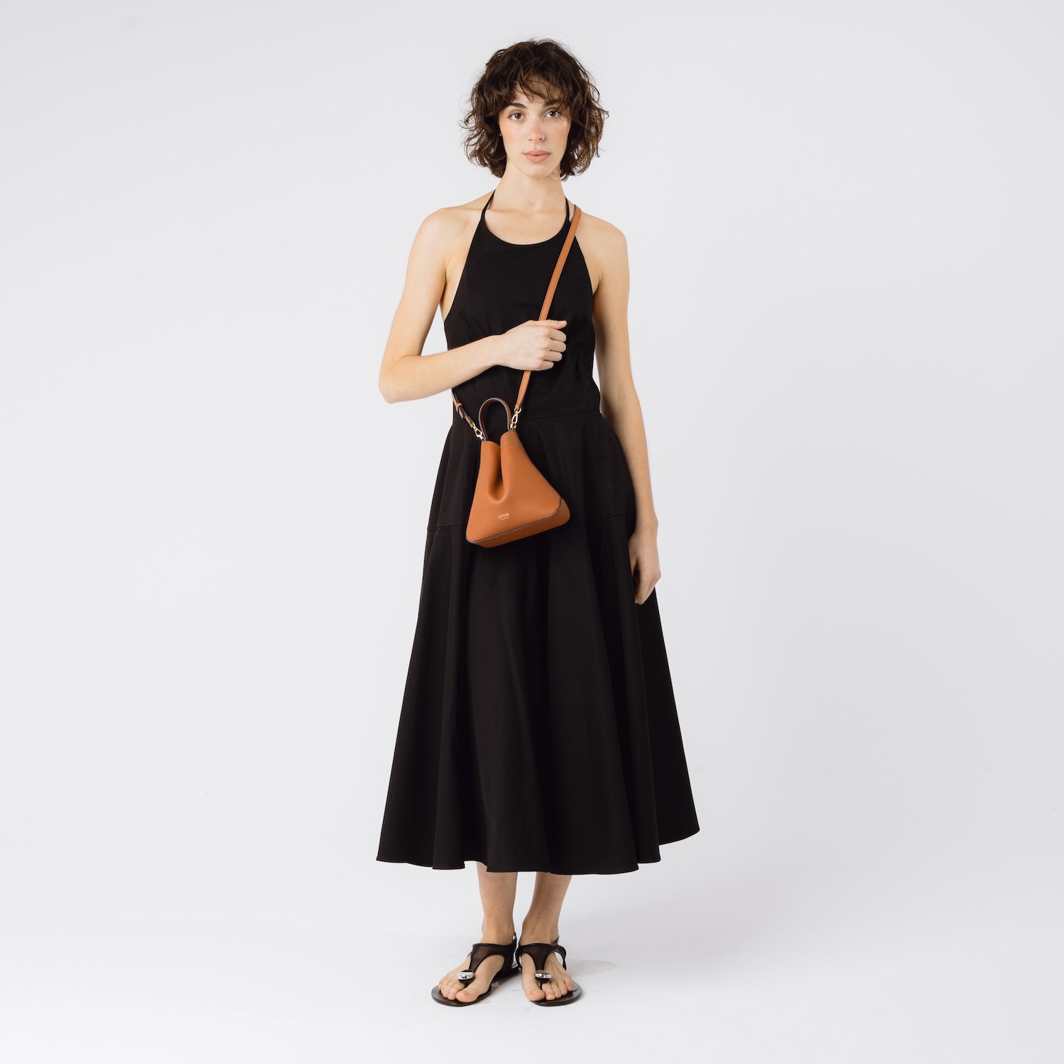 STOW London's Mini Curve in Earth Tan worn crossbody with detachable leather strap by model featuring gold-coated hardware on a white background