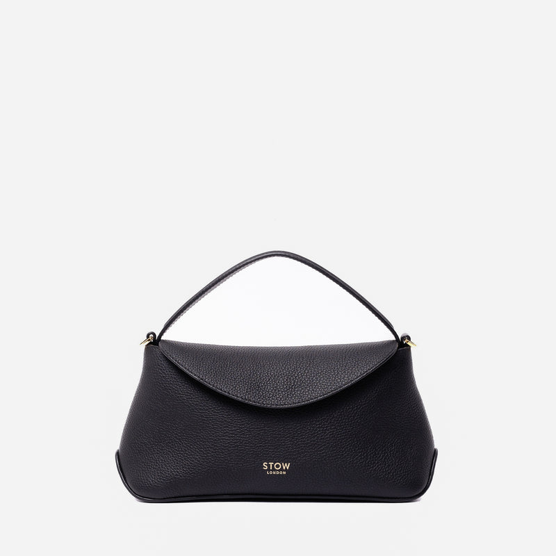 STOW London's Mini East West in Black pebbled leather featuring gold-coated stainless steel hardware on a light grey background