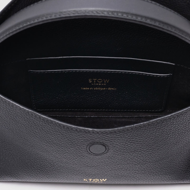 Close up of the interior of STOW London's Mini East West in Black pebbled leather featuring internal slip pocket on a light grey background