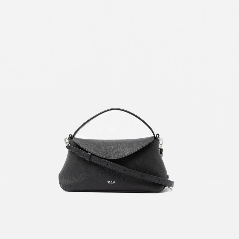 STOW London's Mini East West in Black pebbled leather and detachable crossbody strap featuring silver stainless steel hardware on a light grey background