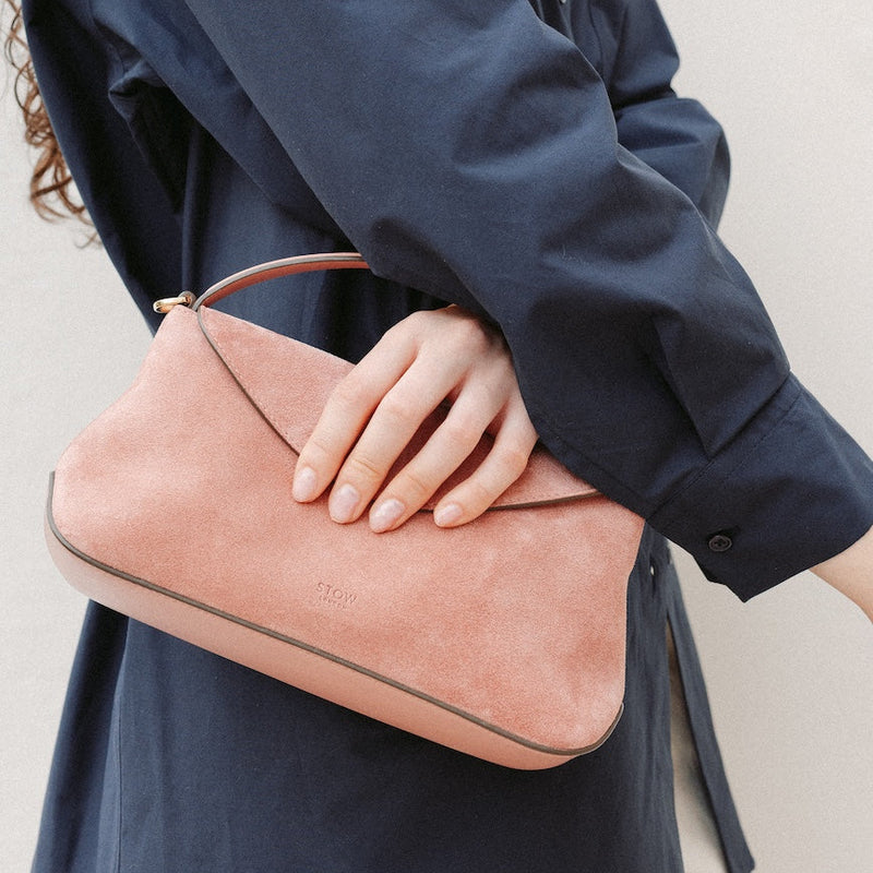 Model holding STOW London's Mini East West in Hazy Blush suede leather featuring gold-coated stainless steel hardware