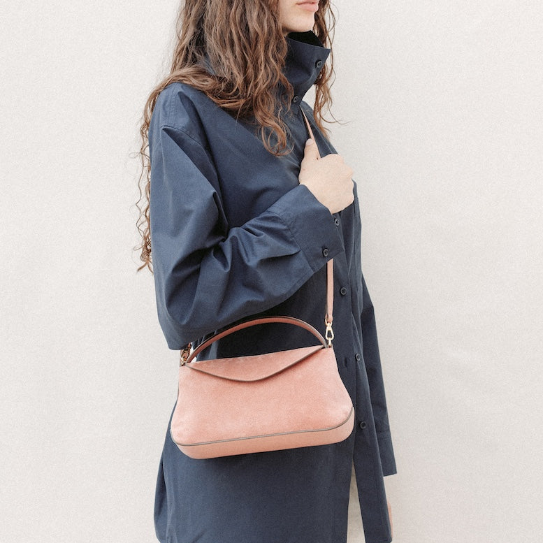 Model wearing STOW London's Mini East West in Hazy Blush suede leather crossbody featuring gold-coated stainless steel hardware