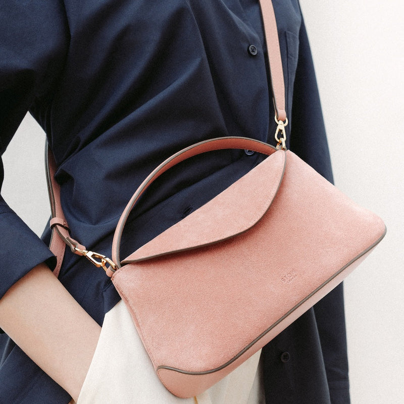 Model wearing STOW London's Mini East West in Hazy Blush suede leather crossbody featuring gold-coated stainless steel hardware