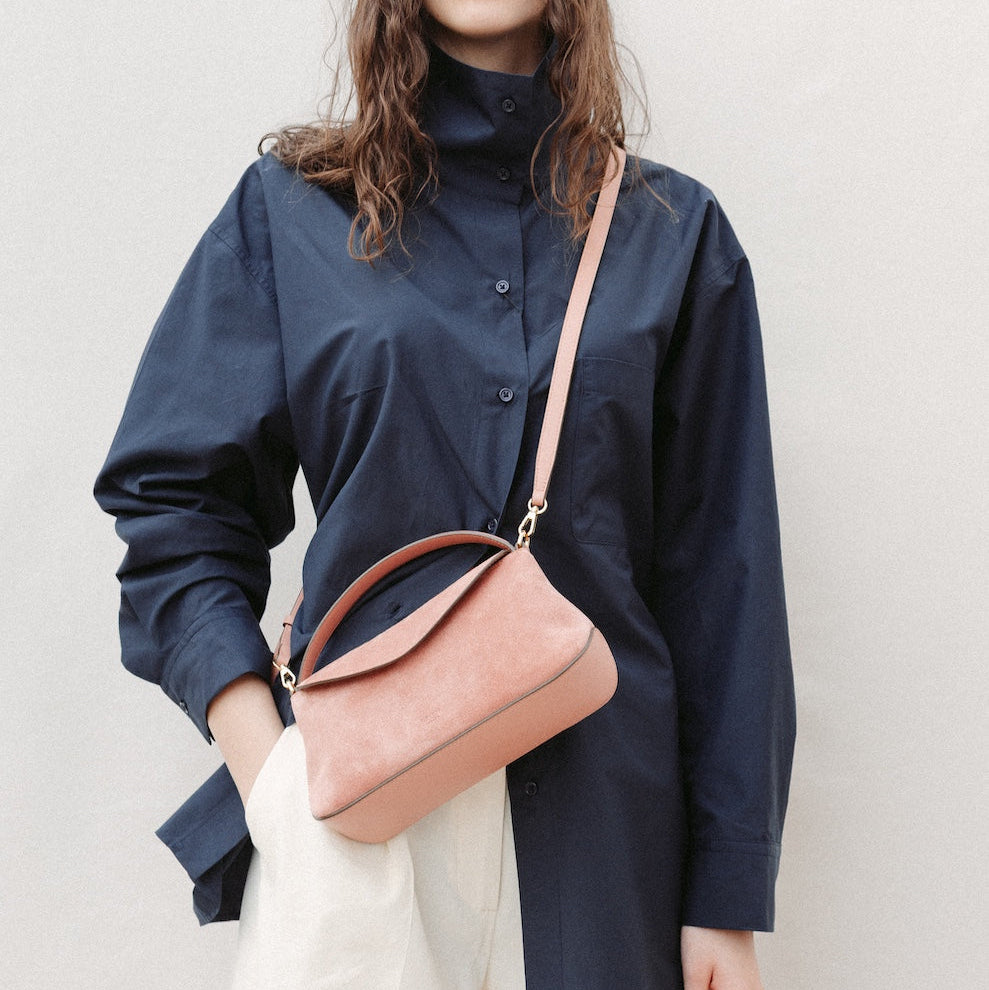 Model wearing STOW London's Mini East West in Hazy Blush suede leather crossbody featuring gold-coated stainless steel hardware