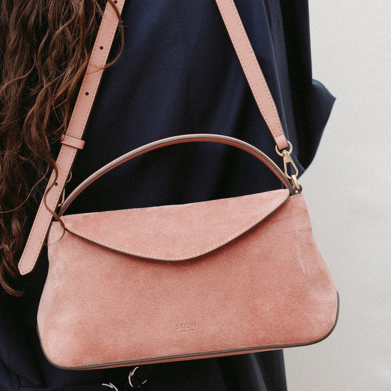 Model holding STOW London's Mini East West in Hazy Blush suede leather featuring gold-coated stainless steel hardware and its detachable crossbody strap