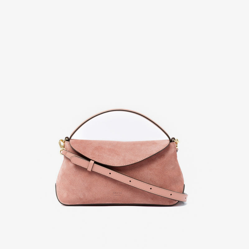 STOW London's Mini East West in Hazy Blush suede leather and detachable crossbody strap featuring gold-coated stainless steel hardware on a light grey background