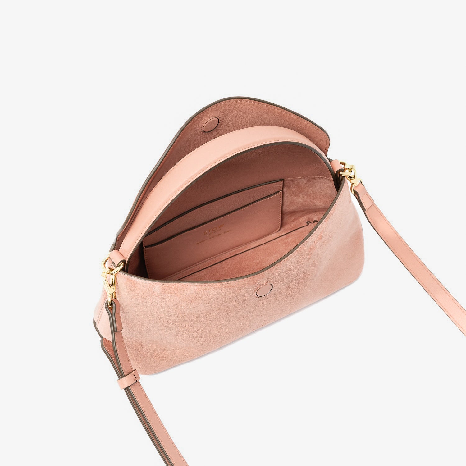 STOW London's Mini East West in Hazy Blush suede leather with flap open showing suede interior and slip pocket featuring gold-coated stainless steel hardware on a light grey background