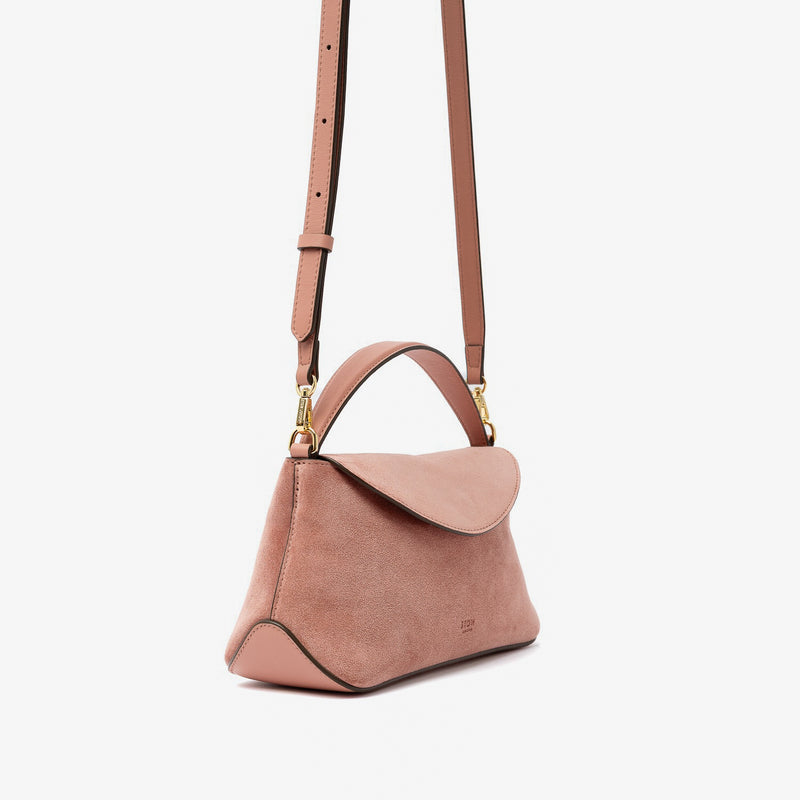 Off-axis view of STOW London's Mini East West in Hazy Blush suede leather and detachable crossbody strap featuring gold-coated stainless steel hardware on a light grey background