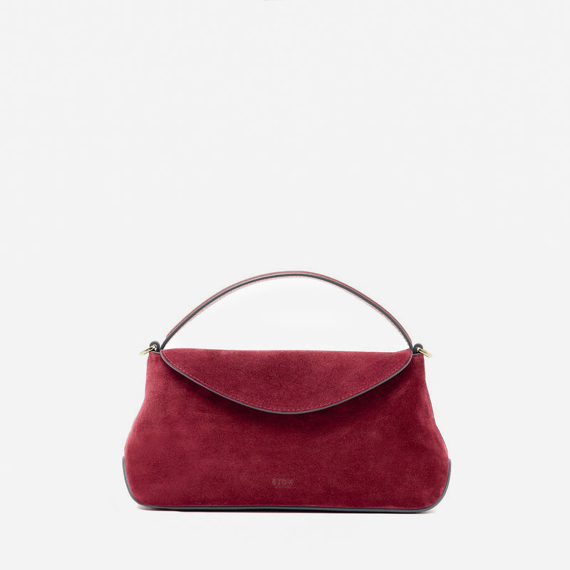 STOW London's Mini East West in Burgundy suede leather featuring gold-coated stainless steel hardware on a light grey background