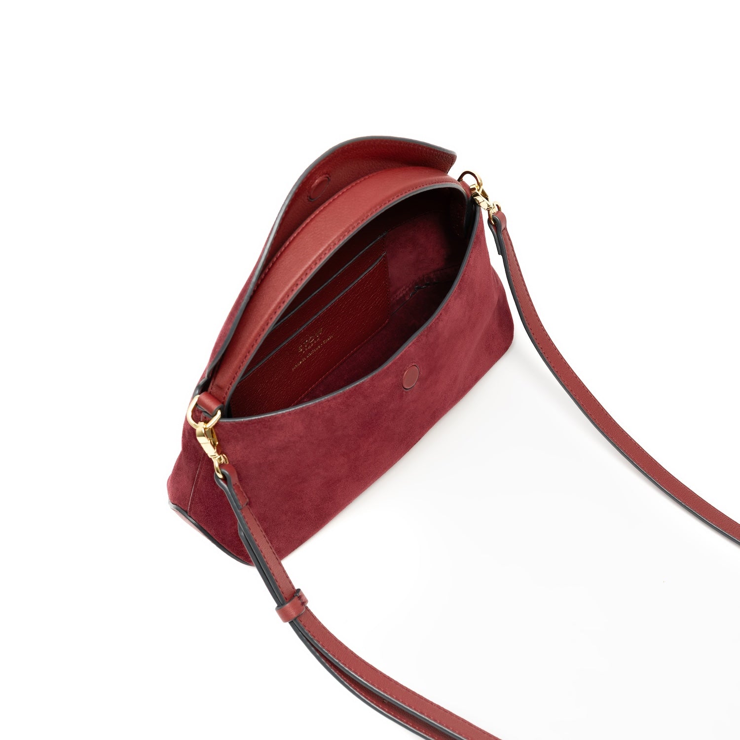 Top view of STOW London's Mini East West bag in Burgundy Suede leather with flap open showing interior card pocket featuring gold-coated stainless steel hardware on a white background
