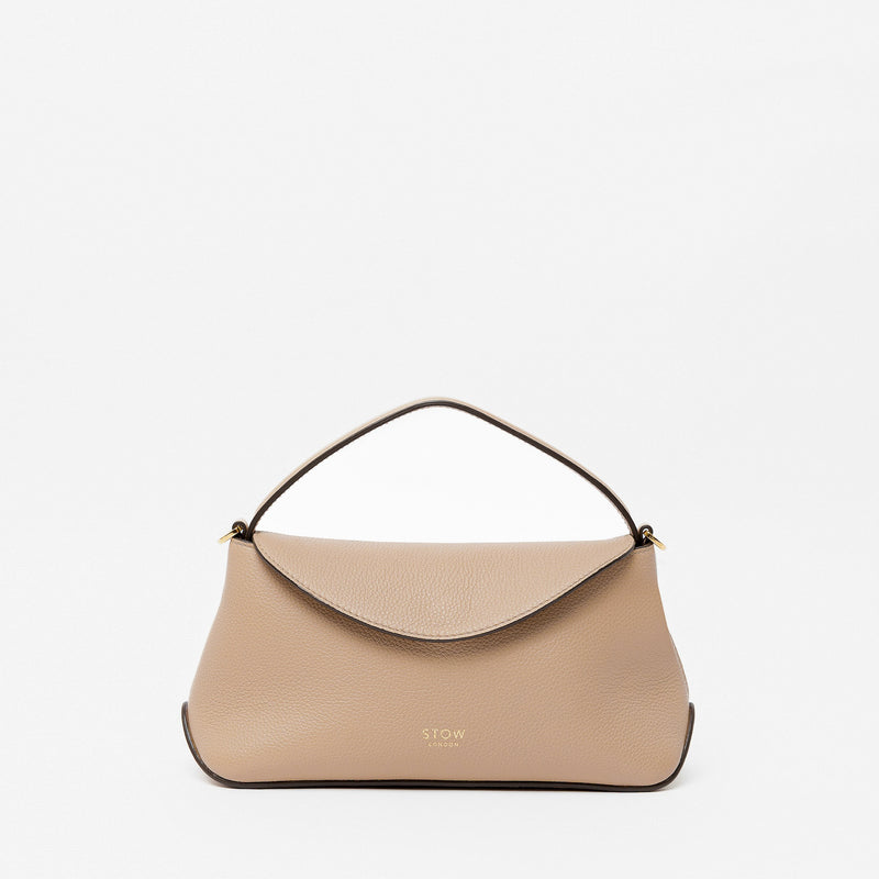 STOW London's Mini East West in Camel pebbled leather featuring gold-coated stainless steel hardware on a light grey background