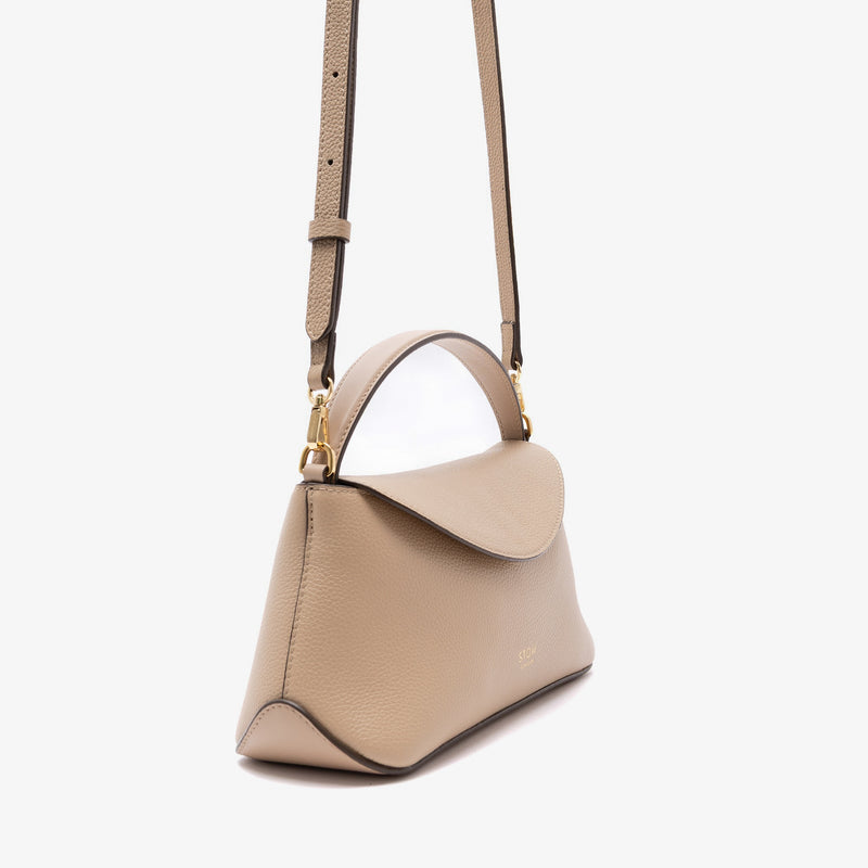Off-axis view of STOW London's Mini East West in Camel pebbled leather and detachable crossbody strap featuring gold-coated stainless steel hardware on a light grey background