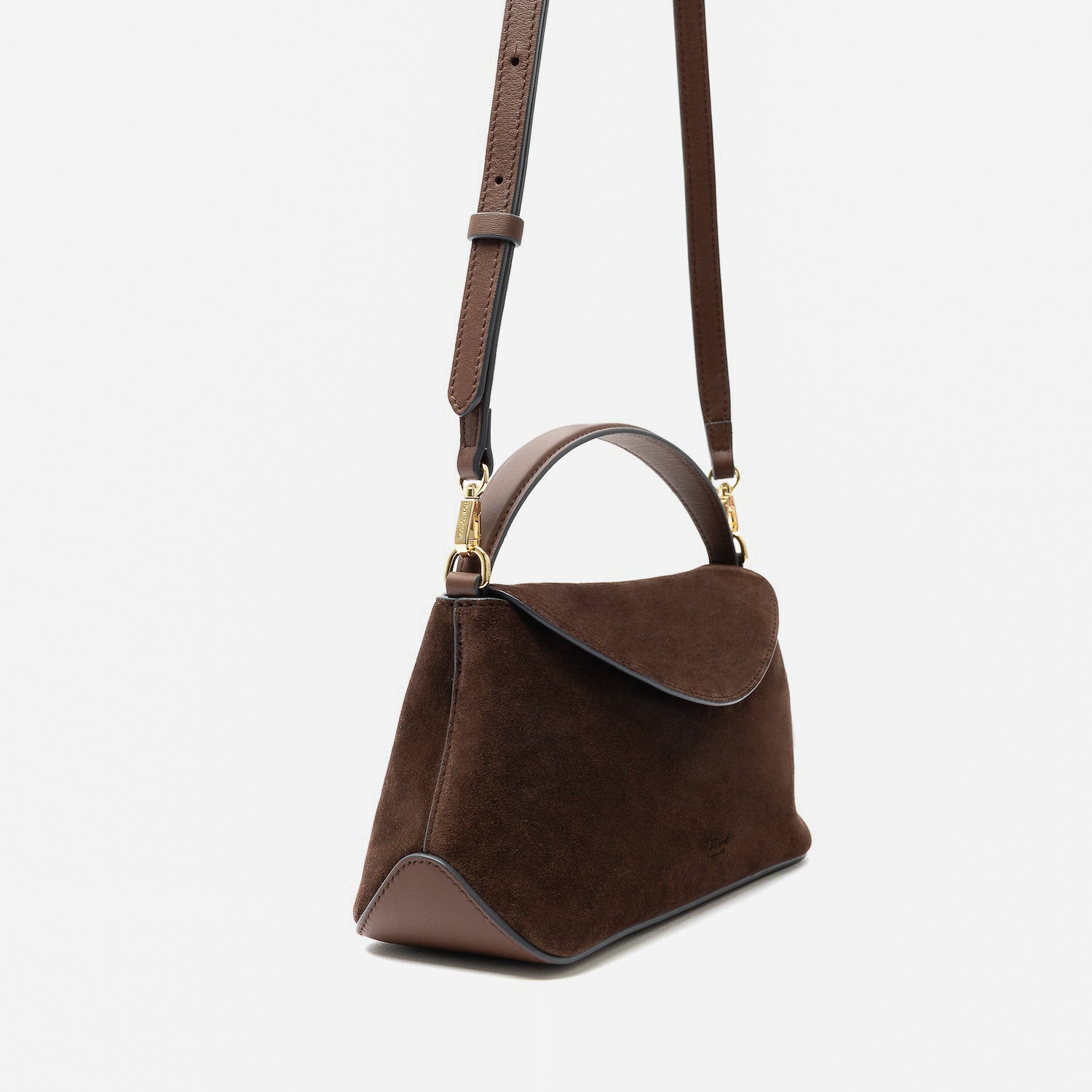 Off-axis view of STOW London's Mini East West in Chocolate suede leather and detachable crossbody strap featuring gold-coated stainless steel hardware on a light grey background