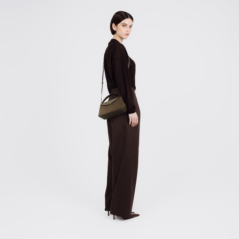 Model wearing STOW London's Mini East West bag in Dark Green Suede leather crossbody featuring gold-coated stainless steel hardware on a white background