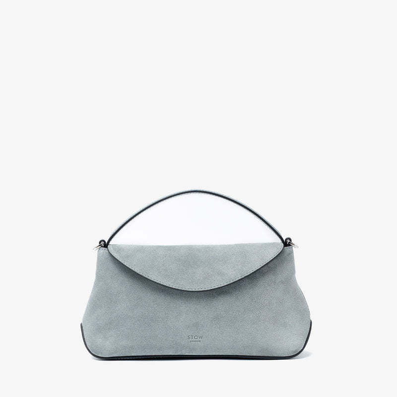 STOW London's Mini East West in Misty Blue suede leather featuring silver stainless steel hardware on a light grey background