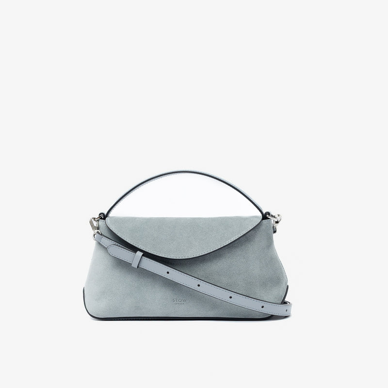 STOW London's Mini East West in Misty Blue suede leather and detachable crossbody strap featuring silver stainless steel hardware on a light grey background
