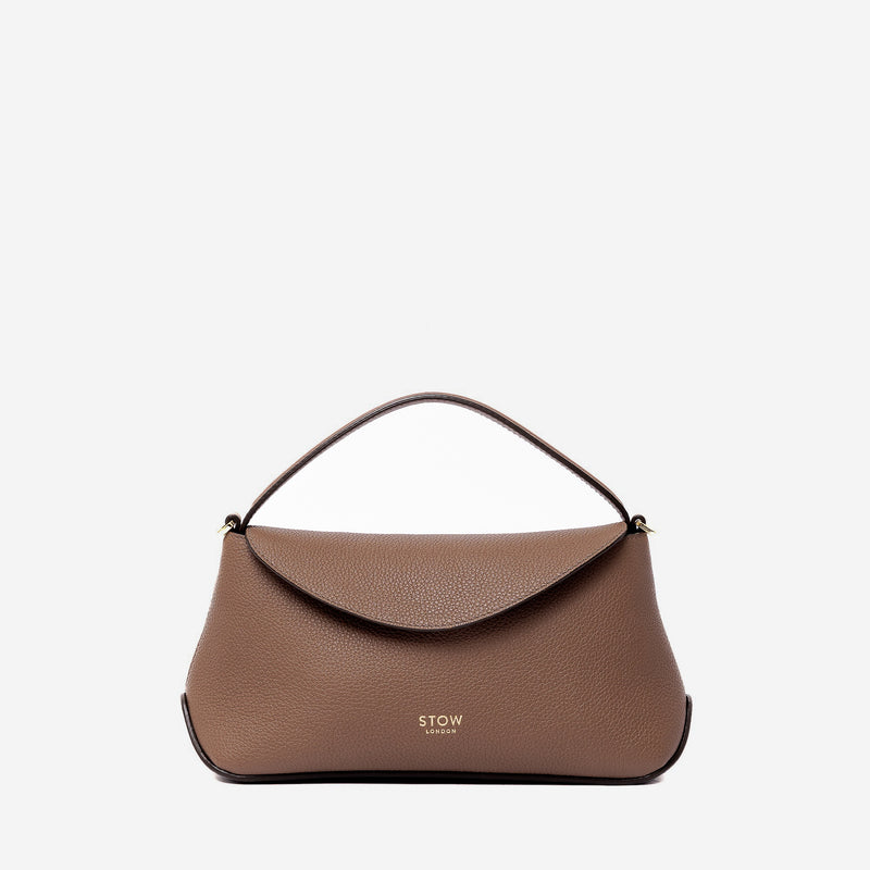 STOW London's Mini East West in Mocha pebbled leather featuring gold-coated stainless steel hardware on a light grey background