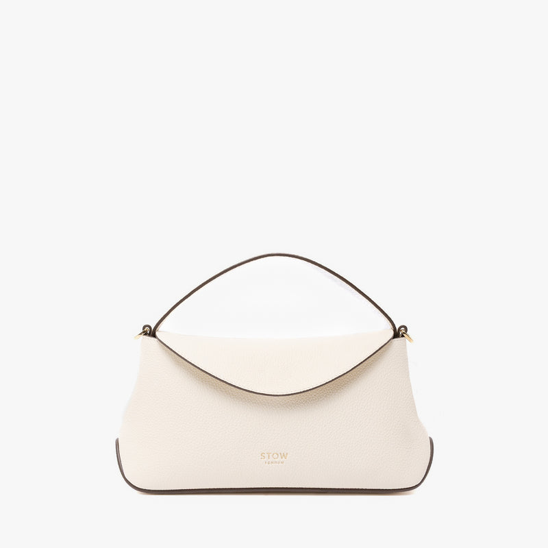 STOW London's Mini East West in Spring Moon pebbled leather featuring gold-coated stainless steel hardware on a light grey background