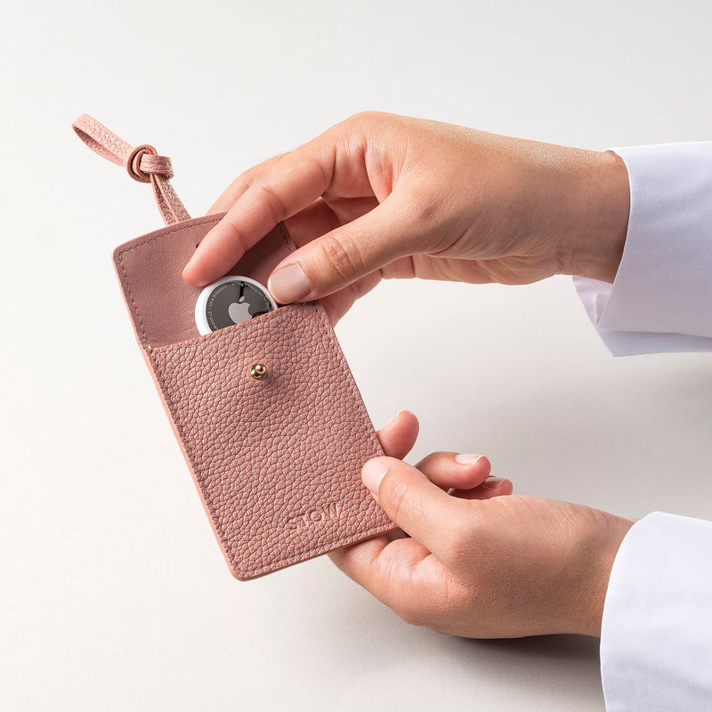 STOW London Leather Multi Tag in Hazy Blush pebbled leather with model placing Apple AirTag inside.