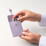 STOW Leather Multi Tag in Wild Lavender with model placing Apple AirTag inside.
