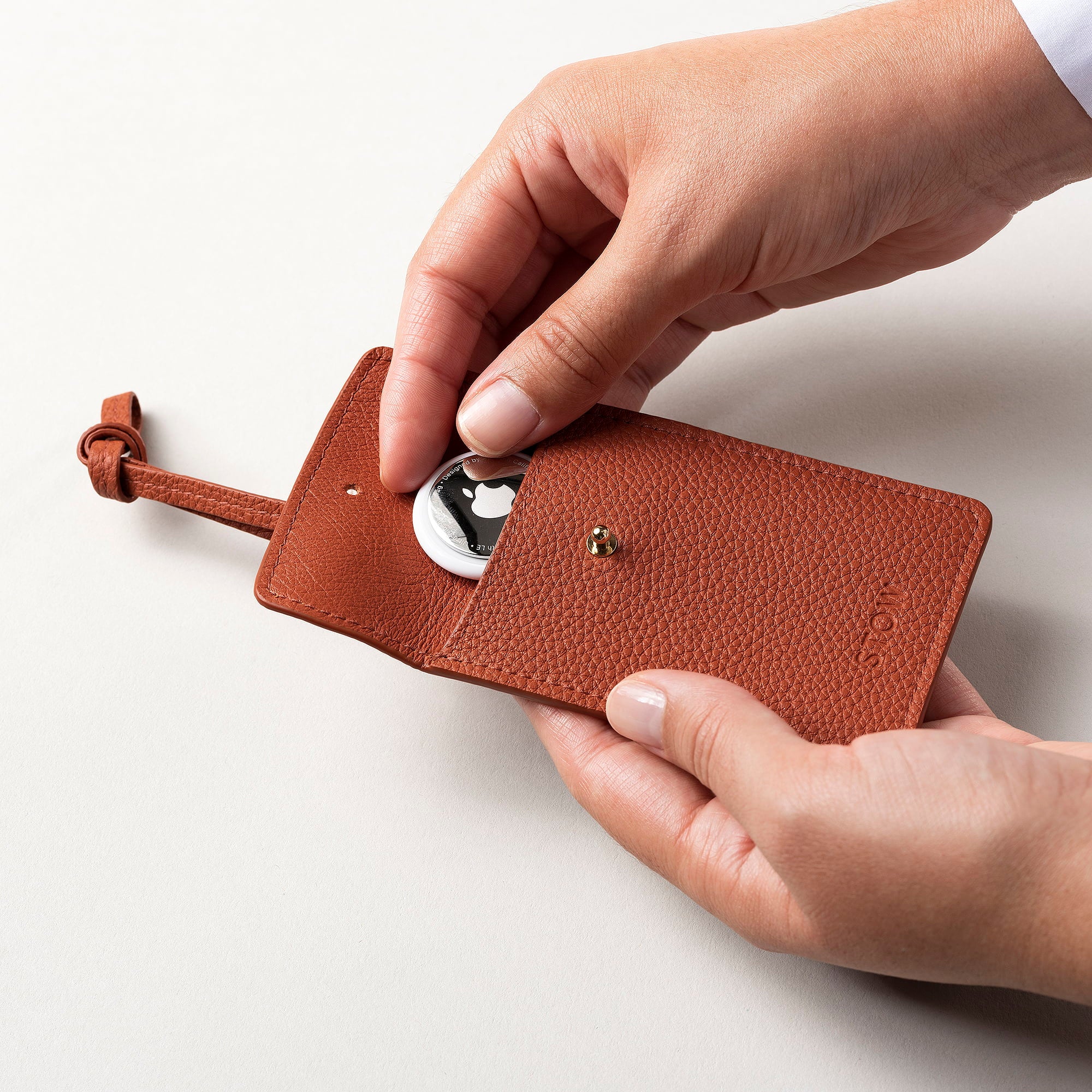 STOW London Leather Multi Tag in Clay Orange pebbled leather with Apple AirTag inside.