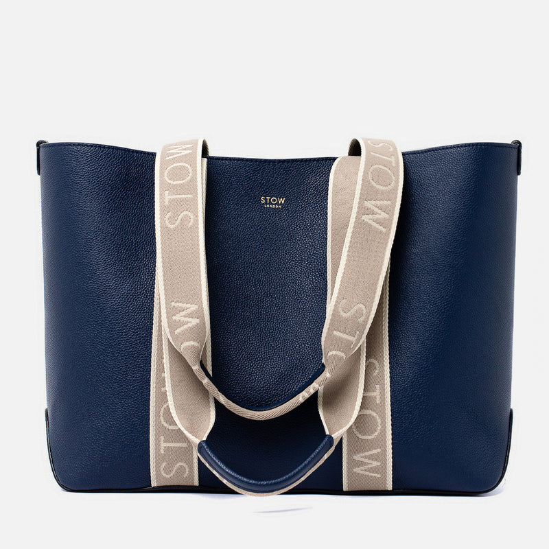STOW London's Nastro Tote bag in Navy pebbled leather with beige nastro handles featuring 'STOW' branding on a light grey background