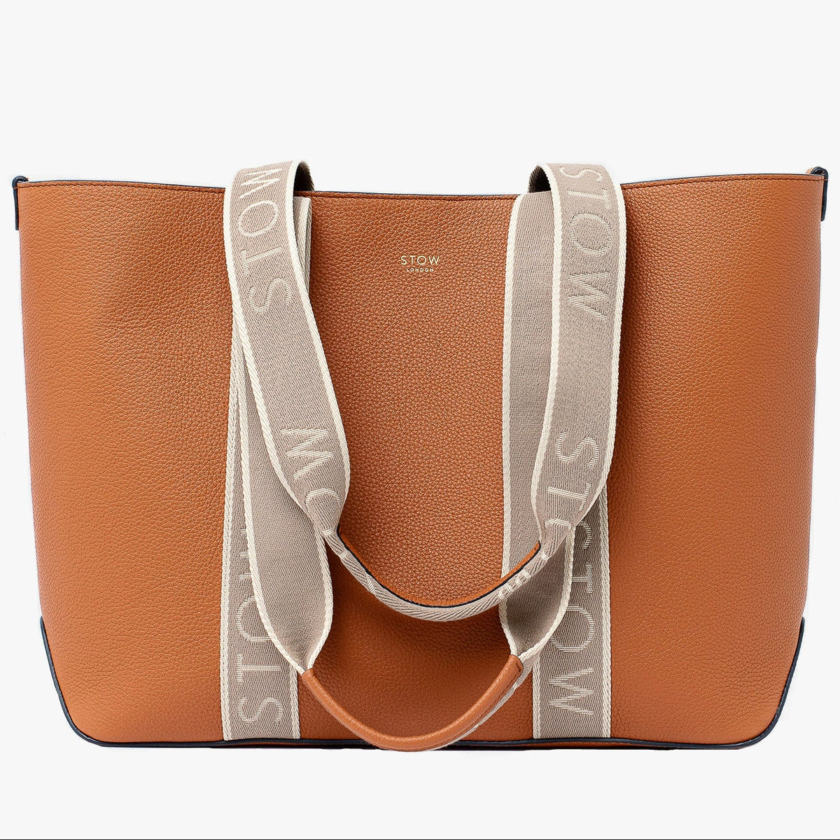 STOW London's Nastro Tote bag in Earth Tan pebbled leather with beige nastro handles featuring 'STOW' branding on a light grey background