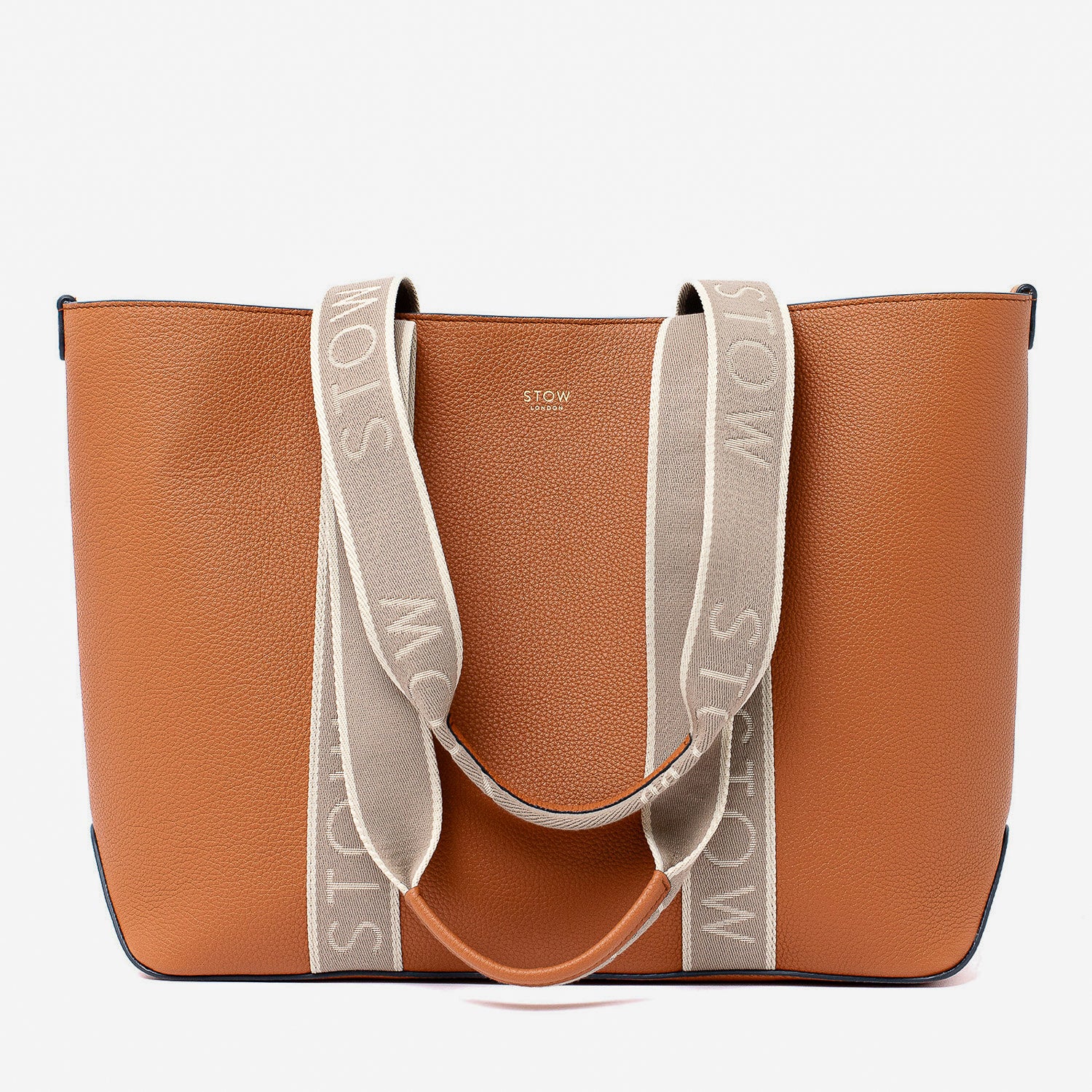 STOW London's Nastro Tote bag in Earth Tan pebbled leather with beige nastro handles featuring 'STOW' branding on a light grey background