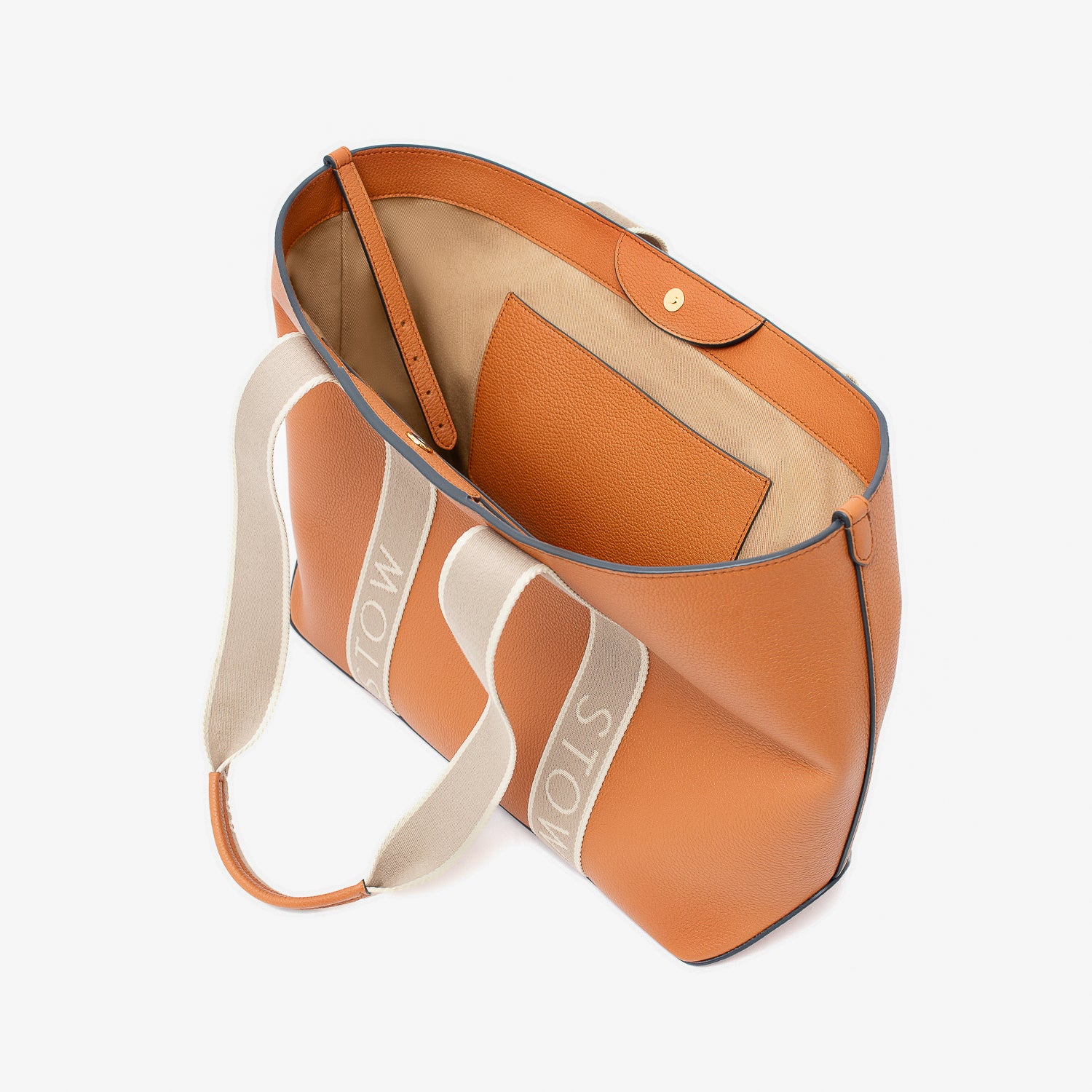 Top view of STOW London's Nastro Tote bag in Earth Tan pebbled leather with magnets open showing cotton interior and slip pocket on a light grey background