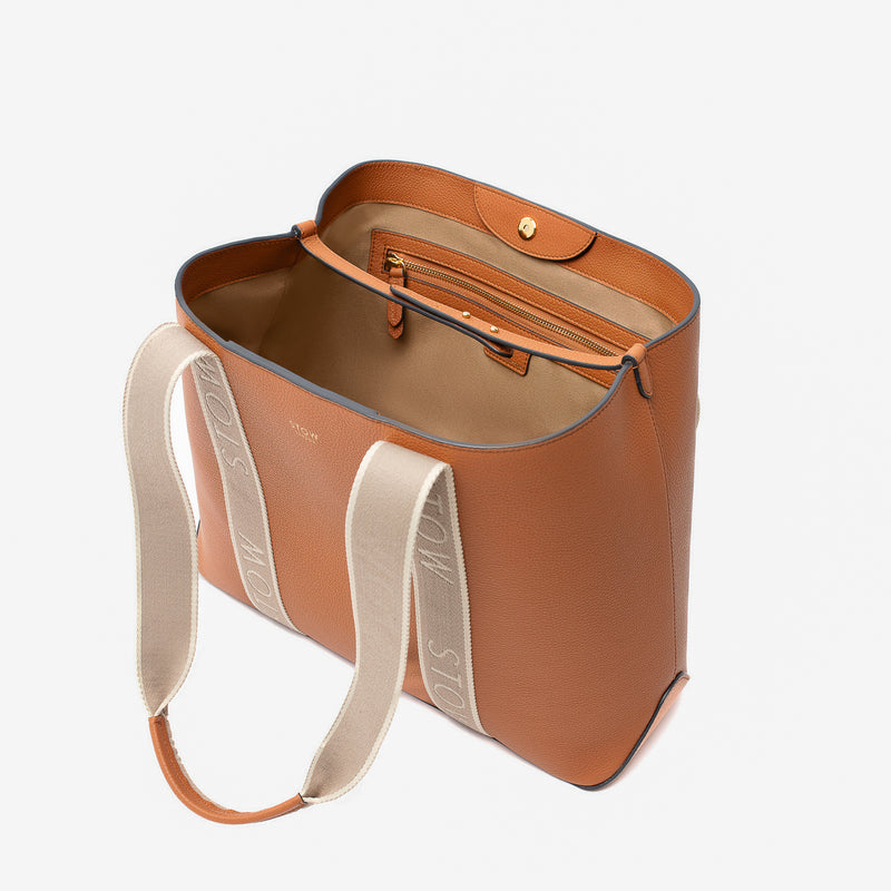 STOW London's Nastro Tote bag in Earth Tan pebbled leather with magnets open showing light beige cotton interior and zip pocket on a light grey background