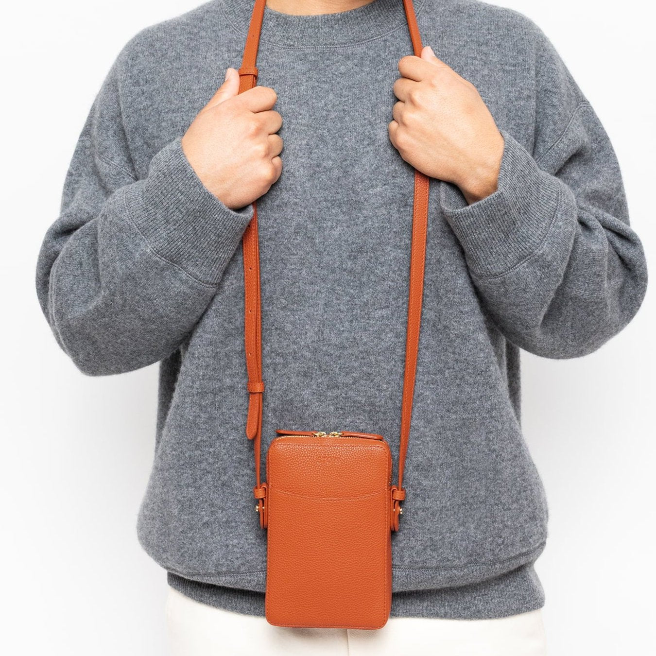 STOW London Clay Orange Phone Crossbody carried by male model