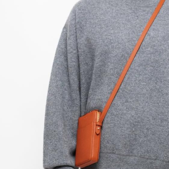 STOW London Clay Orange Phone Crossbody carried by male model