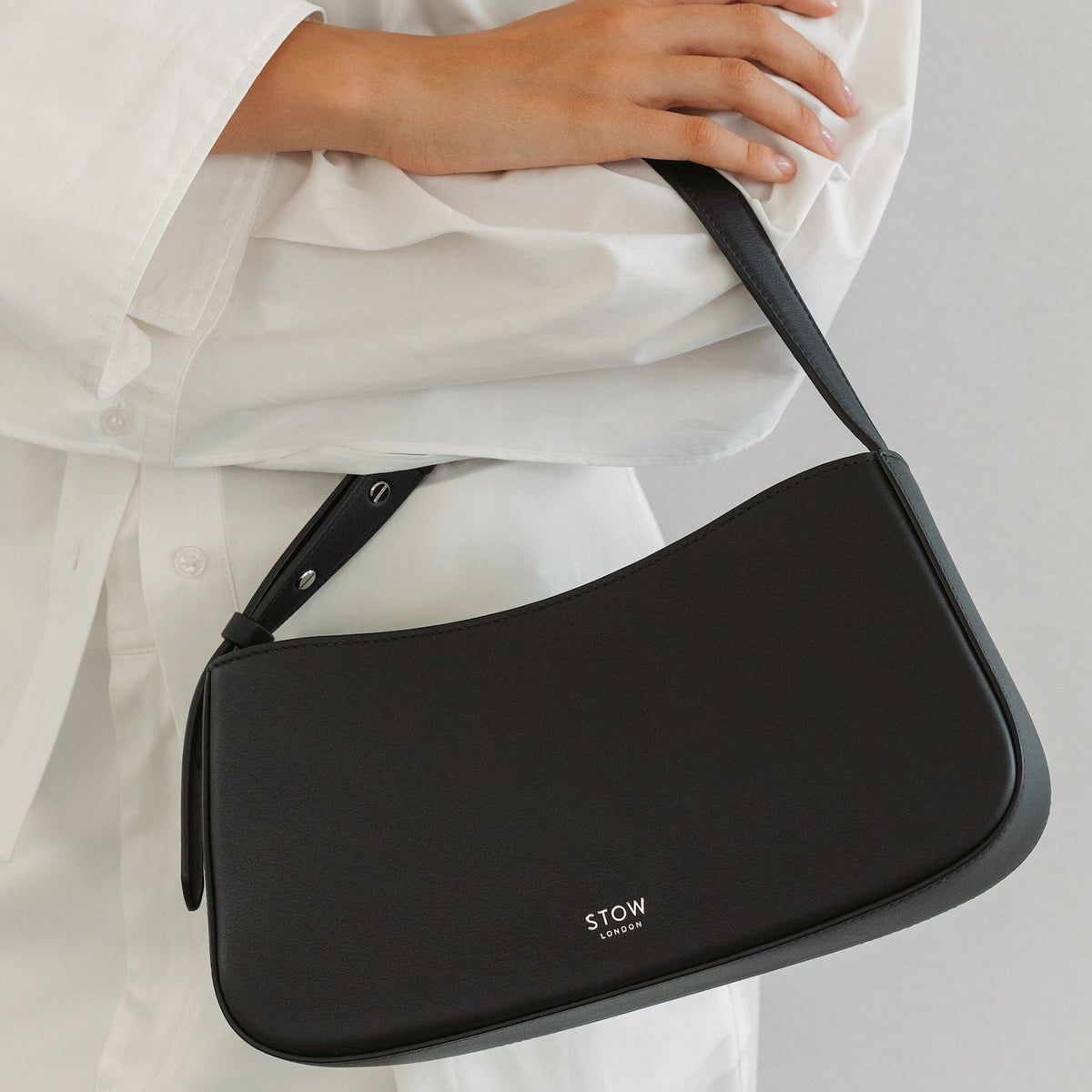 Model with STOW London's Post Shoulder bag in Black smooth leather featuring silver hardware and small embossed logo
