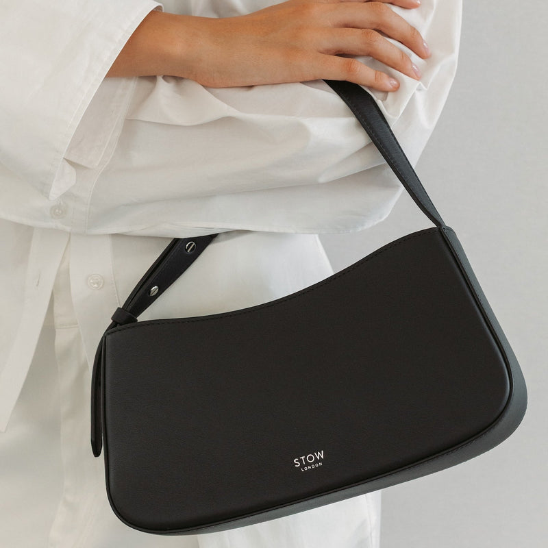 Model with STOW London's Post Shoulder bag in Black smooth leather featuring silver hardware and small embossed logo